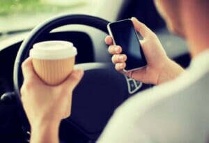 Driver sitting in the car with coffee in one hand and a phone in the other before calling a Lyft Accident Lawyer Tacoma, WA