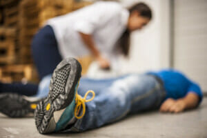 Man lying on the ground with a woman leaning over him, getting ready to contact a Slip And Fall Lawyer Midvale, UT